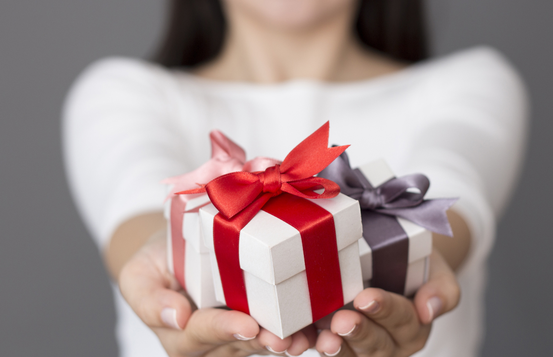 Преподносит приятные сюрпризы. Дарим подарки. Девушка вручает подарок. Подарок в руках. Человек дарит подарок.